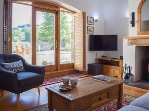 - un salon avec un canapé, une table et une télévision dans l'établissement Barn Cottage, à Talley