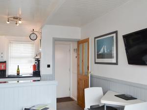 a living room with a table and a tv on the wall at Misty Isles Cottage - S4577 in Ellanbeich