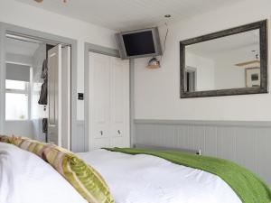 a bedroom with a bed and a tv on the wall at Misty Isles Cottage - S4577 in Ellanbeich