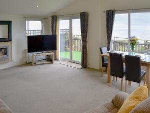 a living room with a television and a table with chairs at Ocean Glade - Uk32963 in Corton