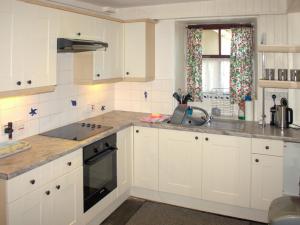 una cocina con armarios blancos y fregadero en Sevenstones, en Trevilley