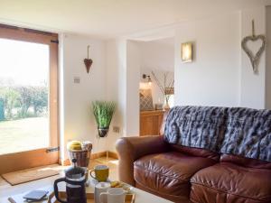 a living room with a brown leather couch and a table at Twin Oaks in Crudgington