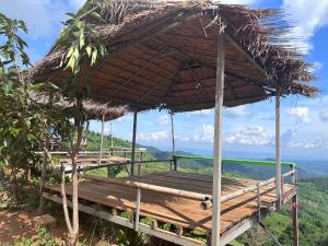 een houten terras met een rieten paraplu bovenop een heuvel bij อาข่าภูมา-Akha Phuma 
