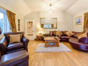 a living room with a leather couch and a table at Forge Gardens in Thornton Dale