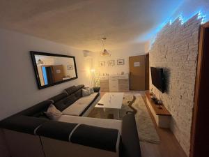 sala de estar con sofá y pared de piedra en Apartman Harmani, en Bihać