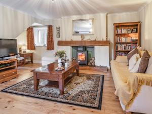 a living room with a couch and a table and a fireplace at Pwll Farmhouse in Llanllawdog