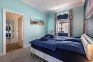 a blue bedroom with a bed and a window at Ferienwohnung am historischen Markt in Friedrichstadt