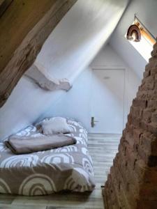 Cama en habitación con pared de ladrillo en Charmante maisonnette en pierre en Écardenville-sur-Eure
