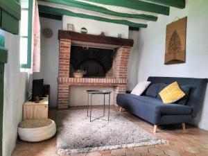 sala de estar con sofá azul y chimenea en Charmante maisonnette en pierre, en Écardenville-sur-Eure