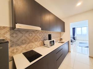 een keuken met bruine kasten en een magnetron bij Ramada Suites by Wyndham The Straits Johor Bahru in Johor Bahru