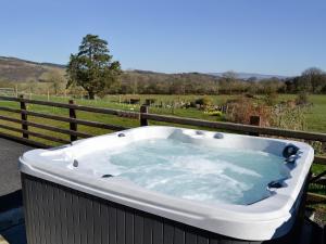 a jacuzzi tub on a deck with a fence at Bryn Melyn - Uk6518 in Frongoch