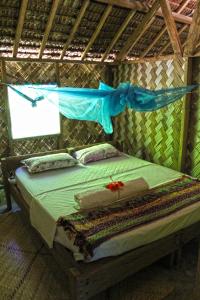 a bed in a tent with a blue net at Nawori Sea View Bungalows N tours Packages in Wortatcha