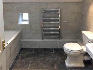 a bathroom with a toilet and a tub and a sink at Inglenook Cottage in Kettlewell