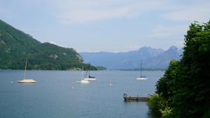 een groep boten drijvend op een meer met bergen bij Villa Alma - a lakeside Boutique Hotel in Sankt Gilgen