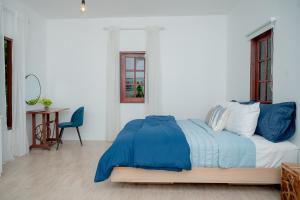 Vawa Guesthouse في مدينة كانشانابوري: غرفة نوم بسرير وملاءات زرقاء وطاولة
