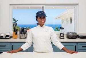 a woman standing in a kitchen with her arms crossed at Hospitality Expert F36 Beach front Pool & Chef in Montego Bay