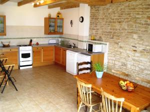 una grande cucina con tavolo in legno, tavolo e sedie di Le Noisetier at Les Hiboux Gites a Chef-Boutonne