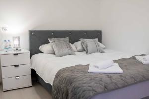 a bedroom with a large bed and a white night stand at The Sun Apartments Brcko in Brčko