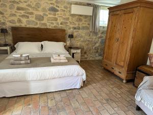 1 dormitorio con 1 cama grande y pared de piedra en Le Mas du Père Jean, en Roche-Saint-Secret