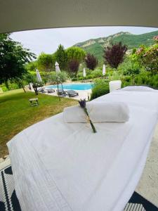 una cama blanca con una servilleta junto a una piscina en Le Mas du Père Jean, en Roche-Saint-Secret