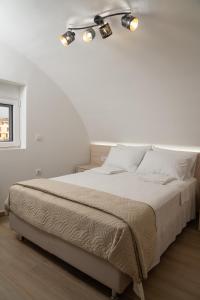 een witte slaapkamer met een bed met twee lampjes erop bij EDEL Suite in Chania +23 foto's