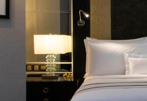 a bedroom with a bed and a lamp on a night stand at The Ritz-Carlton, Kuala Lumpur in Kuala Lumpur