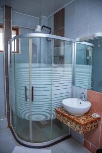 a bathroom with a glass shower and a sink at The Luke Hotel Cravers Thika in Thika