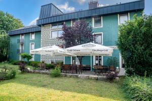a building with tables and umbrellas in front of it at Akzent Hotel Restaurant Hirsch in Heidenheim