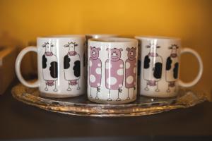 three coffee mugs with cows on them on a plate at Masseria del Bosco - Podere Poderuccio in Chianciano Terme