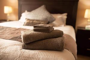 a pile of towels sitting on top of a bed at Spacious 3BR house with a cosy log fire & luxury spa bath in Kalgoorlie