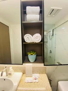 a bathroom with a sink and a shower and towels at Stylish 2 Bedroom Condo Near BGC and Airport with Fast WiFi in Manila