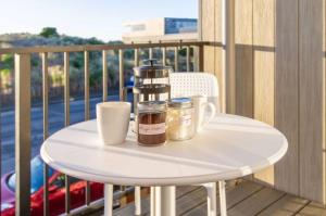 - une table avec deux tasses et une cafetière sur le balcon dans l'établissement Beach Front Abode- 2 Bed 2 Bath, à Christchurch