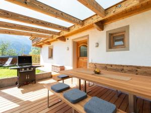 a wooden patio with a table and a grill at beautifully renovated farmhouse Stoanerbauer with a wonderful view in Dorf