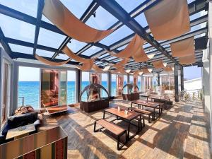 a room with tables and chairs and the ocean at Swiss-Belcourt Kupang in Kupang