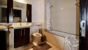 a bathroom with a toilet and a sink and a tub at Rare Holiday Homes welcomes you in - Canal View - The links canal Apartment R304 in Dubai