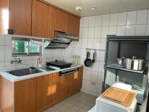 a kitchen with wooden cabinets and a sink and a refrigerator at 埔里北梅民宿BEI MEI Homestay可包棟 in Puli