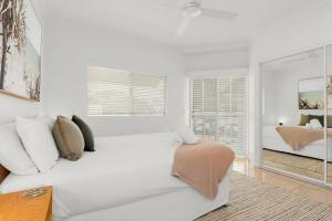 a white bedroom with a large bed and a window at 1 Riverside in Noosaville