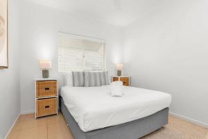a bedroom with a bed with white sheets and two night stands at 1 Riverside in Noosaville