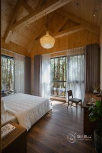 um quarto grande com uma cama grande e uma cadeira em Mơ Stay - Forest Resort em Xuan An