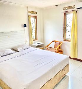 ein Schlafzimmer mit einem großen Bett und einem Stuhl in der Unterkunft HEMRA HOTEL in Balikpapan