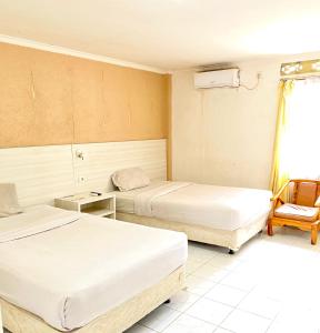 um quarto de hotel com duas camas e uma cadeira em HEMRA HOTEL em Balikpapan