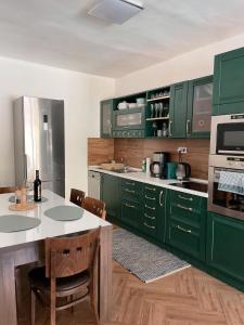 a kitchen with green cabinets and a table with chairs at 4 room flat with garden and pool in Kittsee