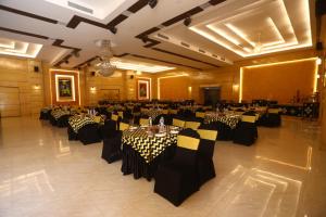 un salón de banquetes con mesas y sillas en blanco y negro en Hotel Kanha’s Palm Springs en Bhopal