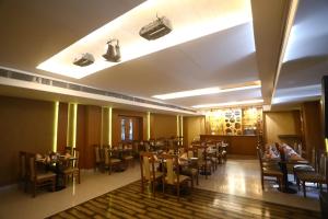 - un restaurant avec des tables et des chaises dans une salle dans l'établissement Hotel Kanha’s Palm Springs, à Bhopal