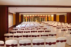 a room with rows of white chairs and a stage at Vishnu Inn in Guruvāyūr