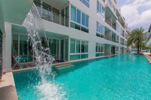 einem Pool mit einem Brunnen vor einem Gebäude in der Unterkunft The Palms, Kamala Beach - SHA Extra Plus in Kamala Beach