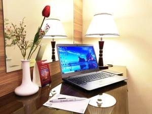 un computer portatile seduto su una scrivania con due lampade di Roshan Al Azhar Hotel a Gedda