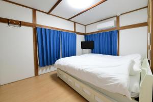 a bedroom with a white bed and blue curtains at JH Yellow Guest House in Tokyo