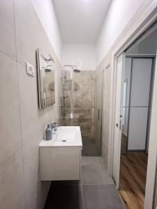 a white bathroom with a sink and a shower at Chariming and Comfy Studio in Pula