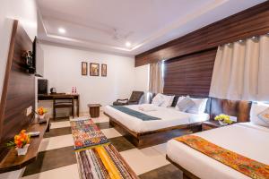 a hotel room with two beds and a couch at Hotel Naman in Udaipur